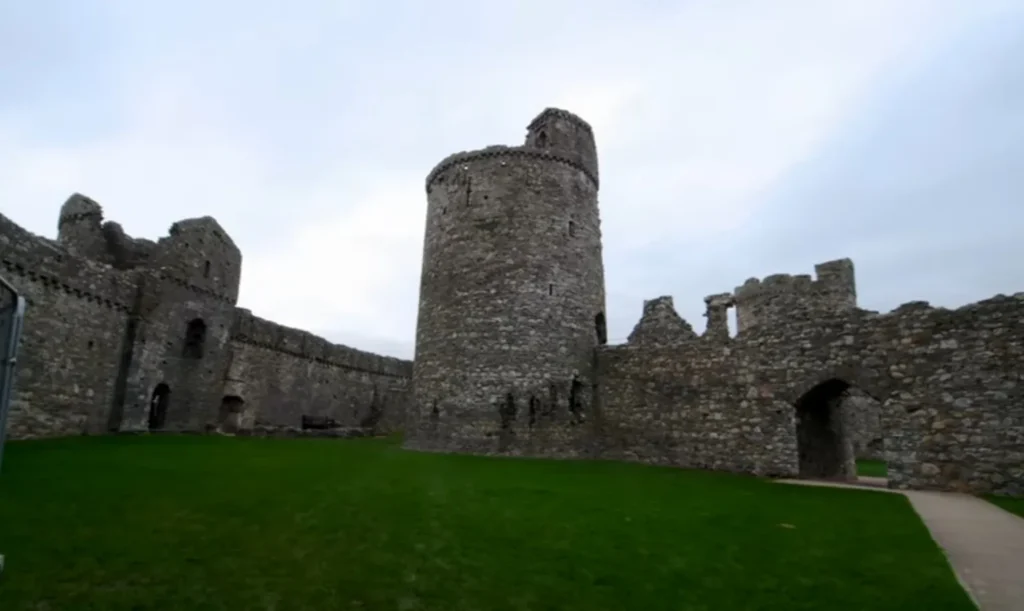 A wide-angle perspective of Kidwelly Castle’s inner courtyard, with its towering circular keep and fortified walls still standing strong. The well-preserved ruins provide a glimpse into the medieval past, where knights and soldiers once patrolled these historic grounds