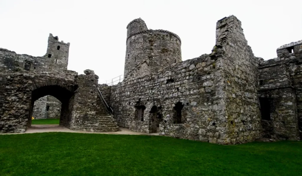 A view inside the ruins of Kidwelly Castle, showcasing its medieval stone walls, stairways, and defensive towers. The remnants of the stronghold highlight its rich history of warfare and resilience, standing as a symbol of Norman power in Wales.
